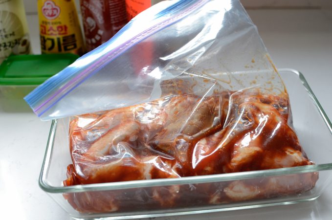 Chicken party wings are mixed with a marinade in a plastic bag.