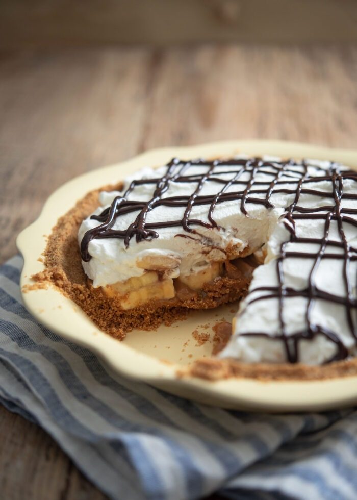 A piece of slice is taken out from the whole banoffee pie.