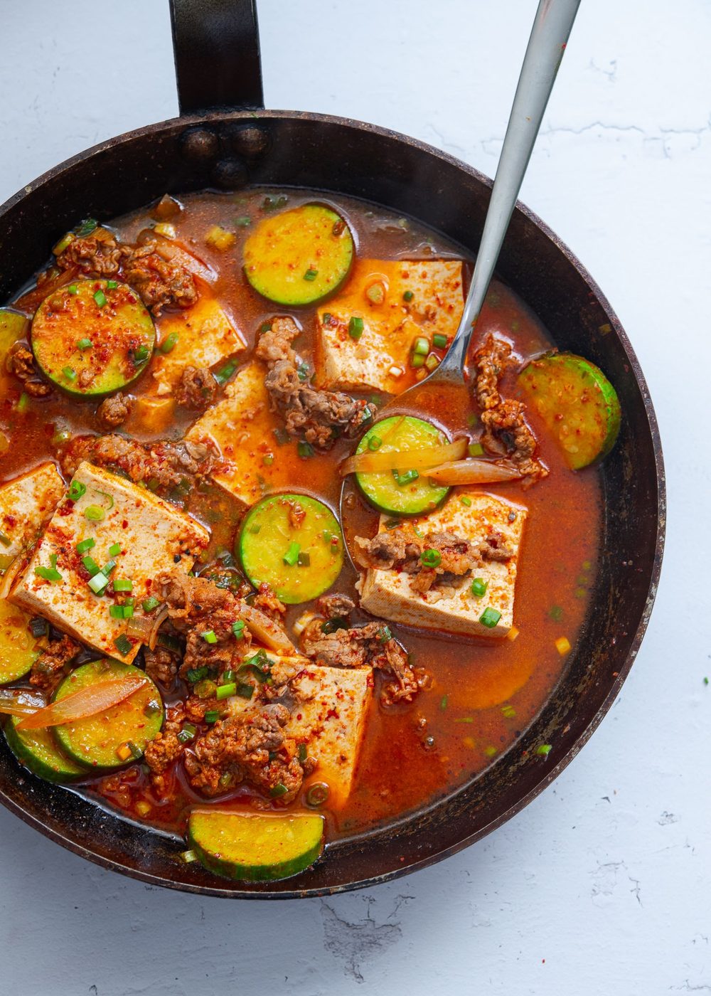 Beef and tofu stew with zucchini in a skillet.