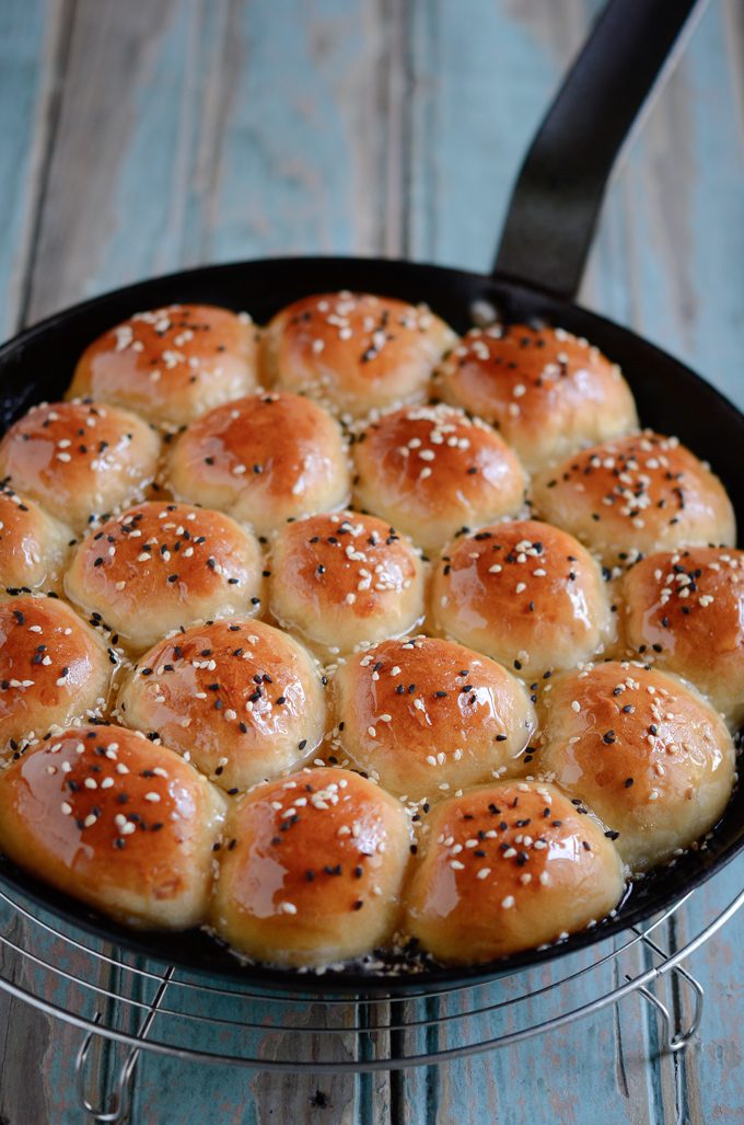 Honeycomb patterned beehive sweet buns are soaked in honey syrup in a skillet.
