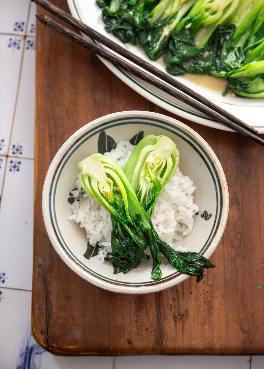 Bok choy stir-fry with garlic and sauce, served over white rice in a ceramic bowl