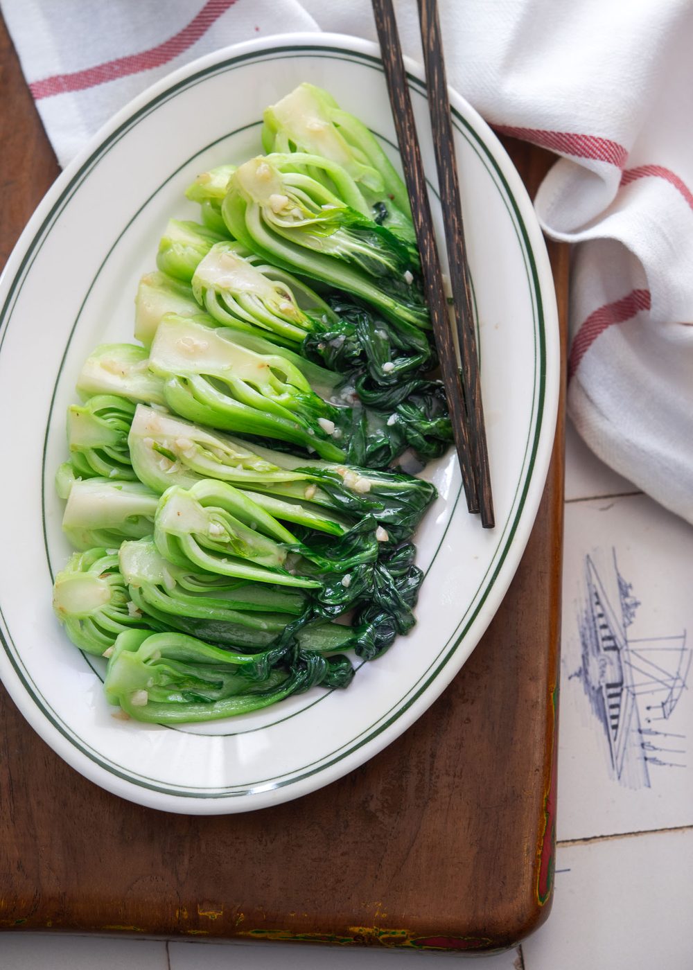 Chinese-style stir-fried bok choy with garlic and glossy sauce on a white plate.