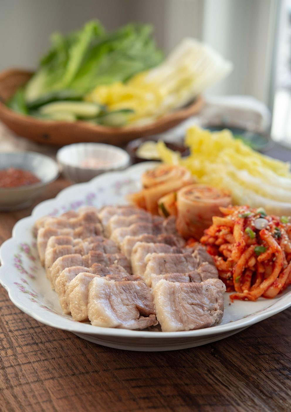 Korean bossam platter with sliced pork belly, cabbage leaves, and spicy radish kimchi.