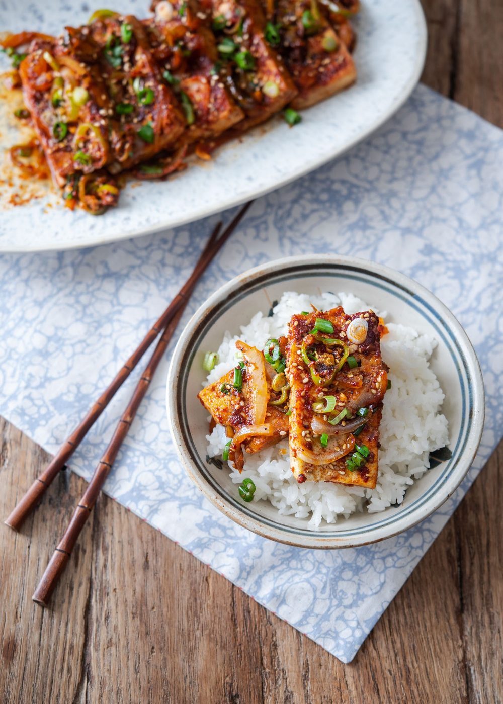 Sliced Korean braised tofu placed on top of warm rice in a bowl