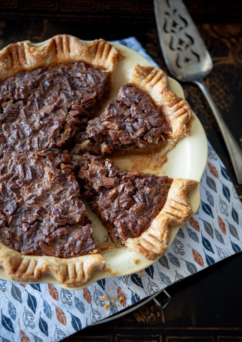 Two piece of butterscotch pie is sliced from the whole pie showing flaky crust.