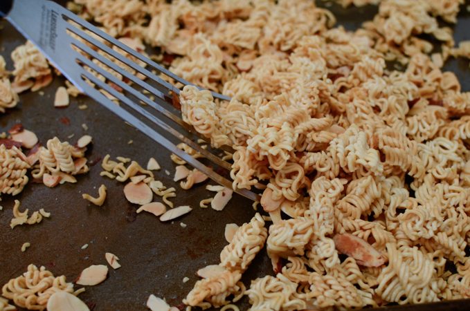 Ramen noodles and almond slices are toasted until golden crisp.