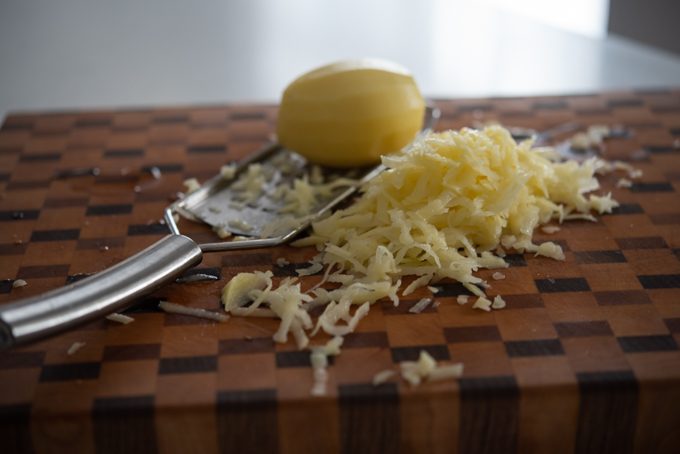 Shredded potato on a cutting board.