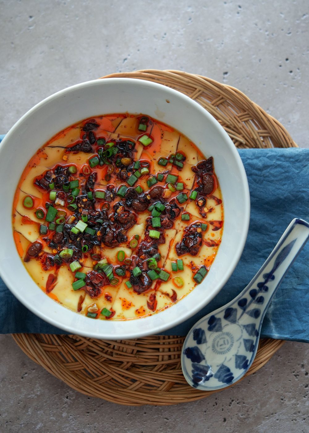 A bowl of Chinese steamed eggs with a spoon.