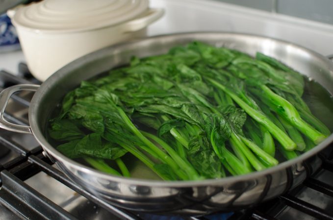 Yu choy stems and leaves simmering in water