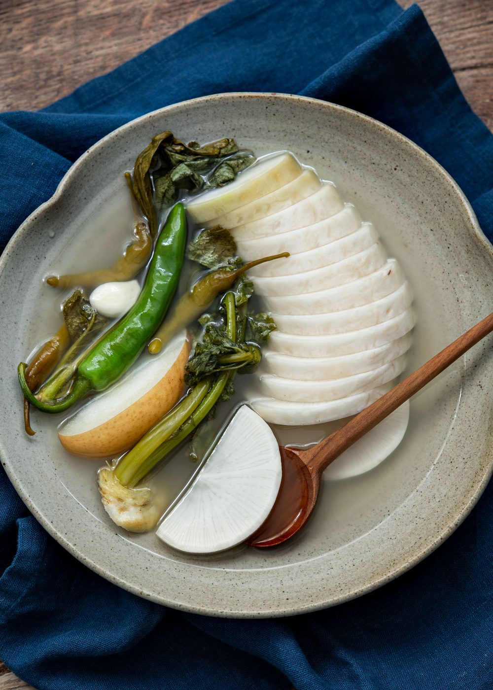 Sliced Korean radish arranged in a bowl of clear dongchimi brine