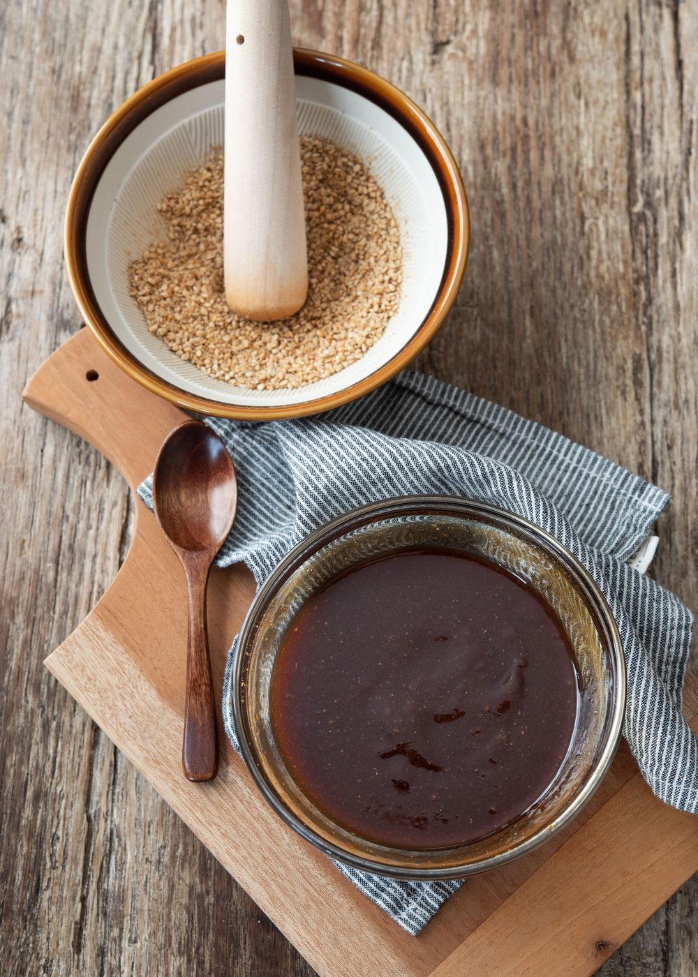 Kitchen-made tonkatsu sauce in a bowl is next to the freshly crushed sesame seeds.