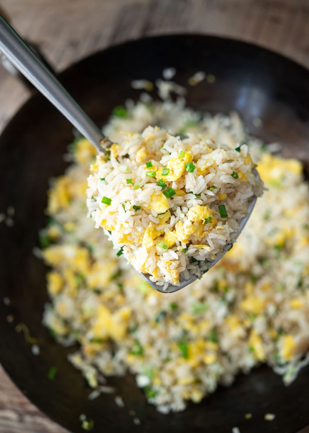 Spatula lifting egg fried rice from a wok
