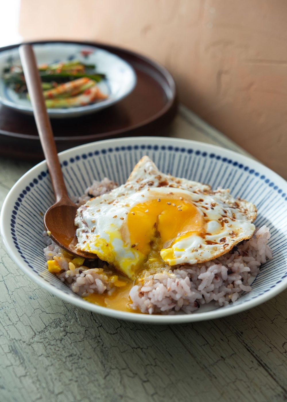 Runny egg yolk over warm rice in a bowl of gyeran bap.