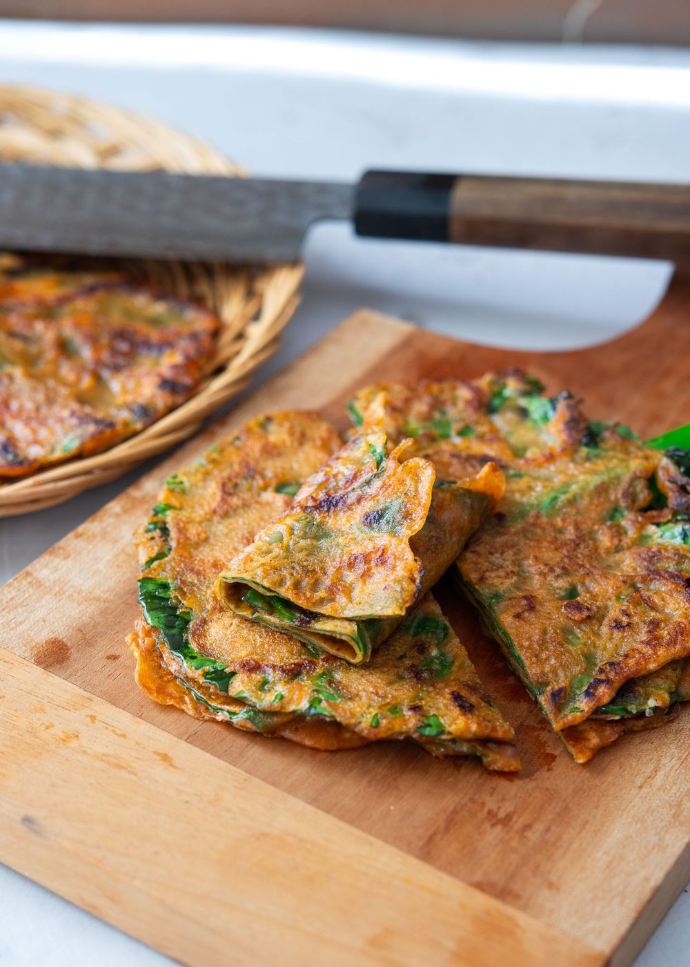 Sliced kale gochujang pancakes (jangtteok) on a cutting board