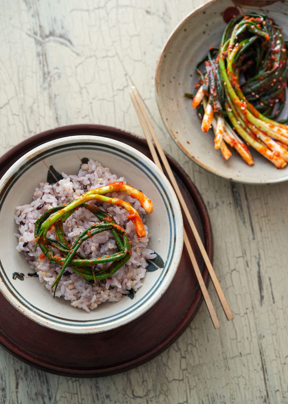 A couple strands of Pa Kimchi are placed on a bowl of rice.