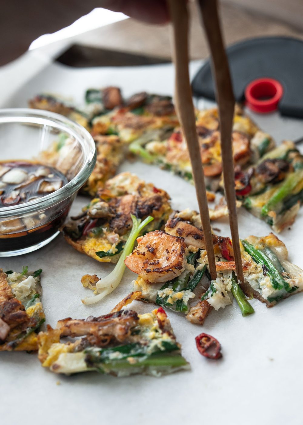 A pair of chopsticks picking up a piece of crispy haemul pajeon.