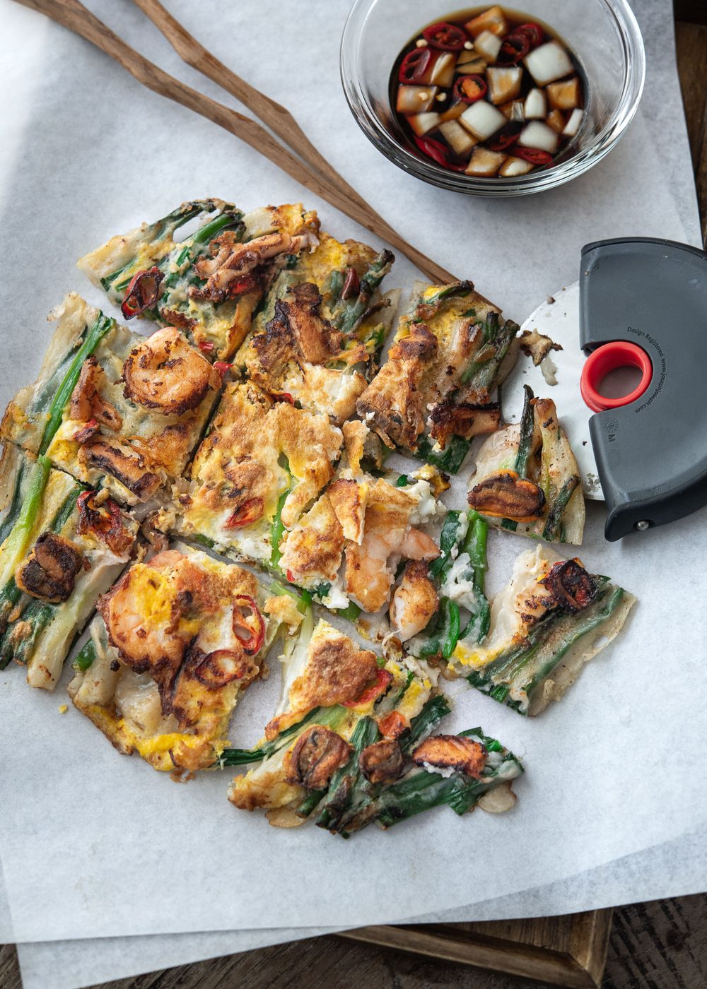 Pajeon with seafood is cut into slices and served with dipping sauce.