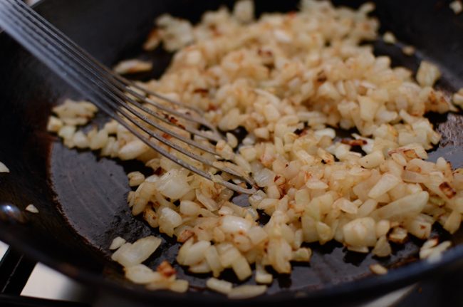 Chopped onion is caramelizing in a skillet.