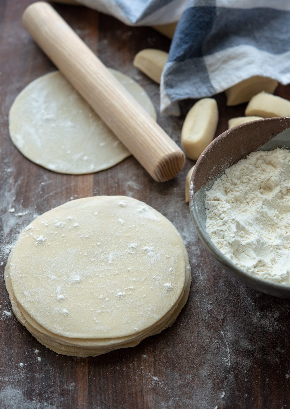 A rolling pin on top of dumpling wrappers.
