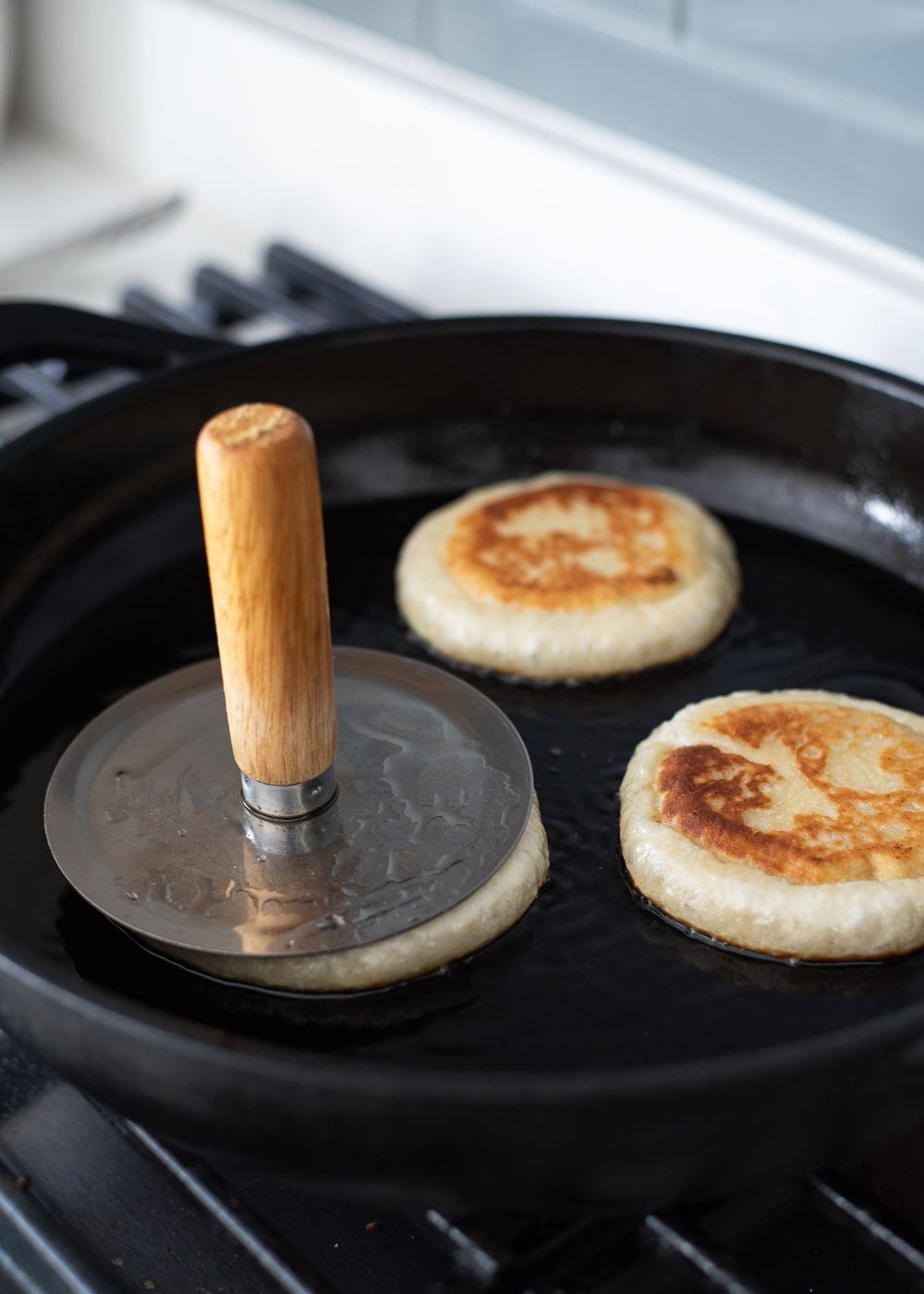 Flattening hotteok dough in a skillet with a hotteok press.