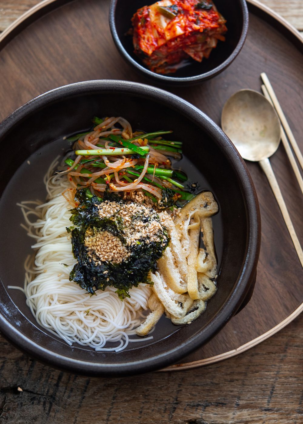 Bowl of janchi guksu, Korean wheat noodles in anchovy broth with vibrant toppings.