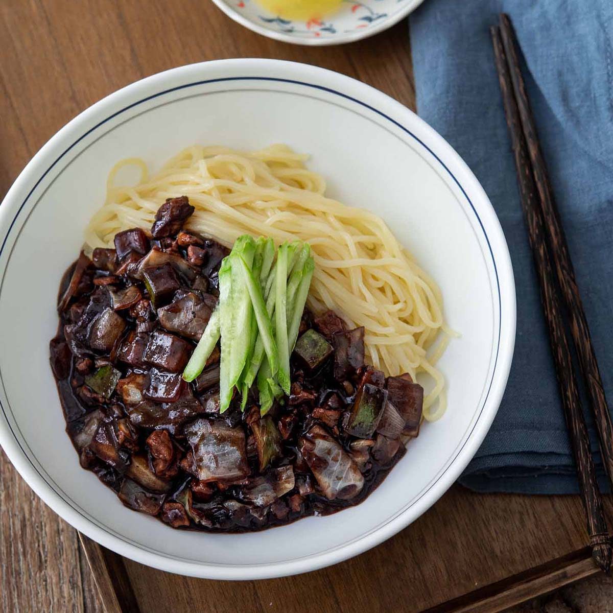 A bowl of jajangmyeon (Korean black bean noodles) garnished with cucumber.