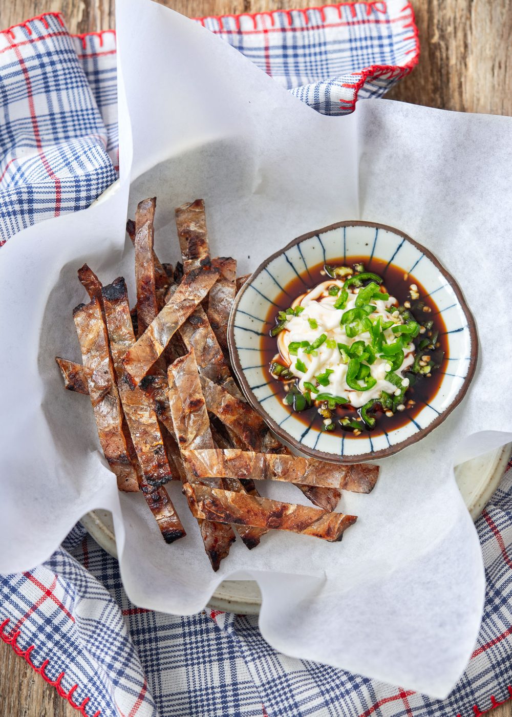 Korean fish jerky is placed with dipping sauce on the side in a serving dish.