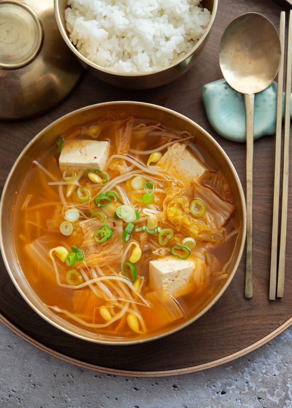 A bowl of kimchi soybean sprout soup served on a tray.