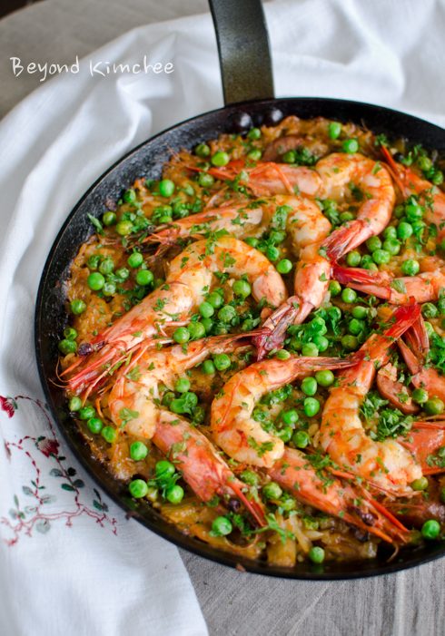 This Korean fusion paella with kimchi, shrimp and peas are cooked in a skillet.