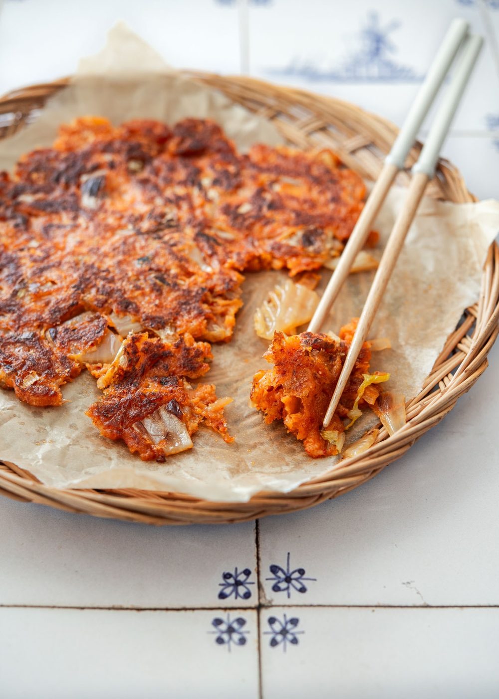 Piece of crispy kimchi pancake (kimchi jeon) picked up with chopsticks