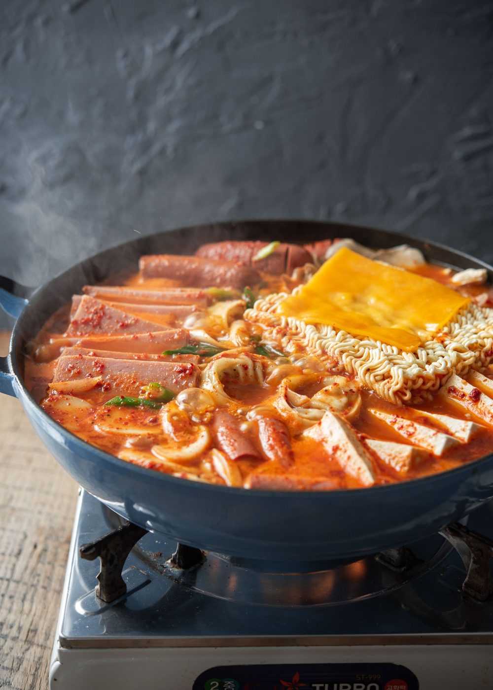 Budae jjigae, Korean army stew, cooking over a portable burner with assorted ingredients.