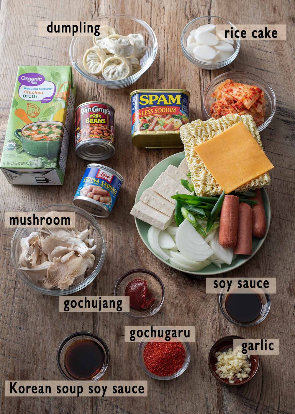 Ingredients for budae jjigae, including Spam, sausage, tofu, kimchi, and ramen noodles.