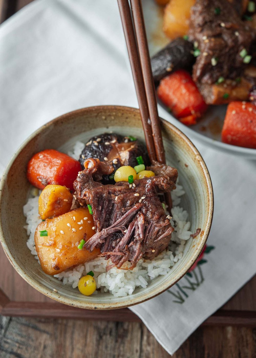Tender braised beef short ribs with vegetables served over rice