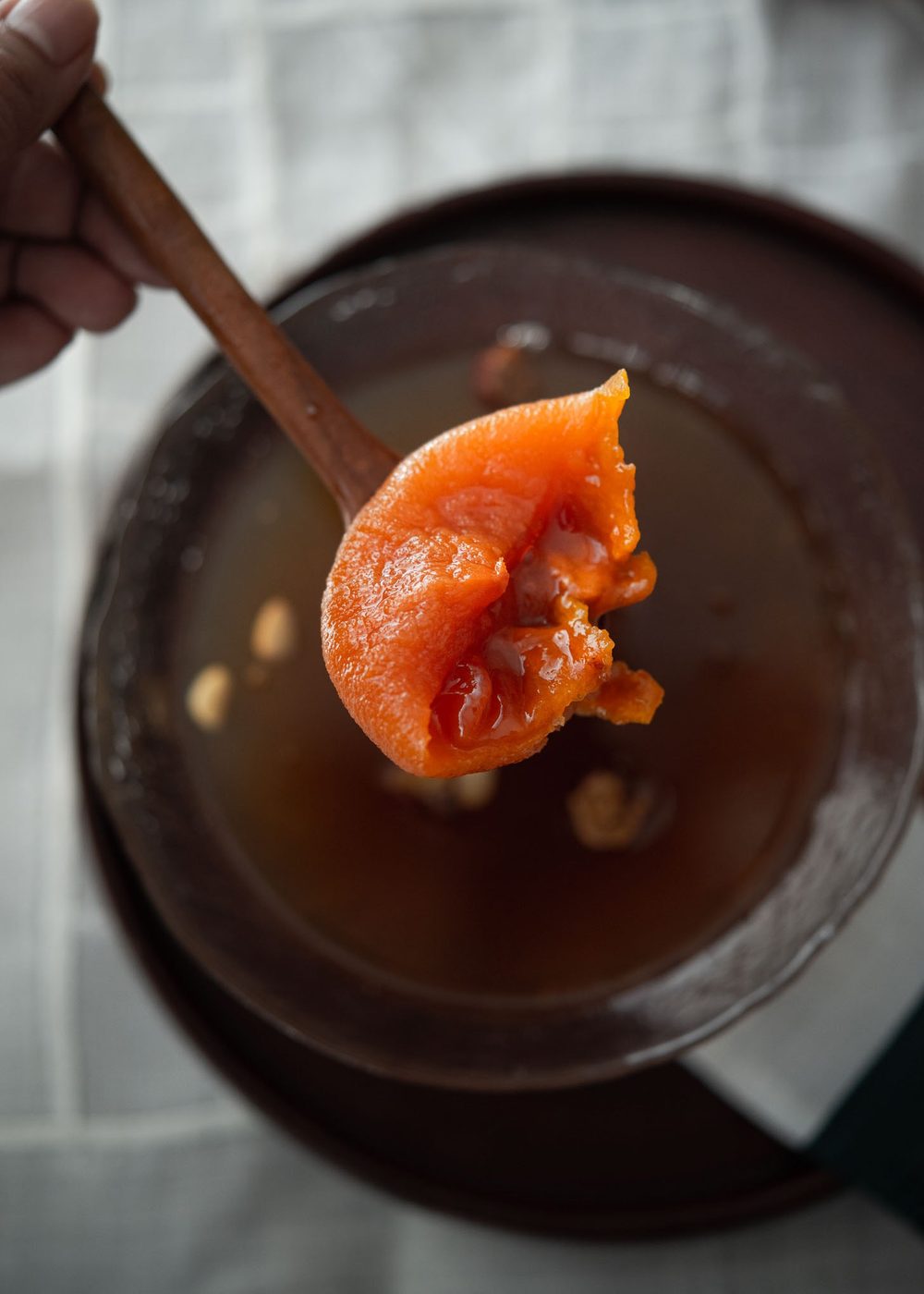 Plumped and softened dried persimmon soaking in a bowl of sujeonggwa, Korean cinnamon drink