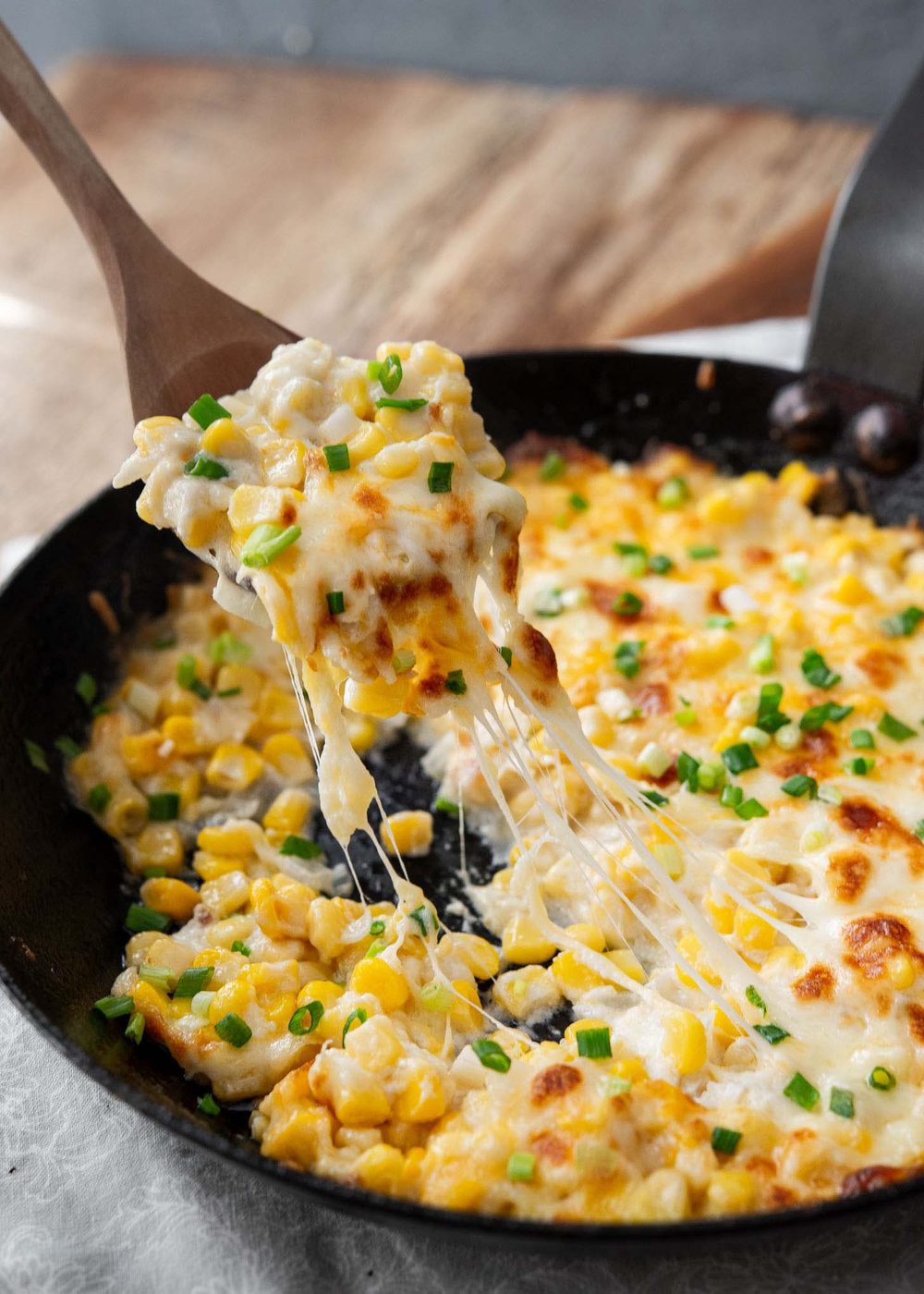 Spoon lifting hot corn cheese with melted cheese strands