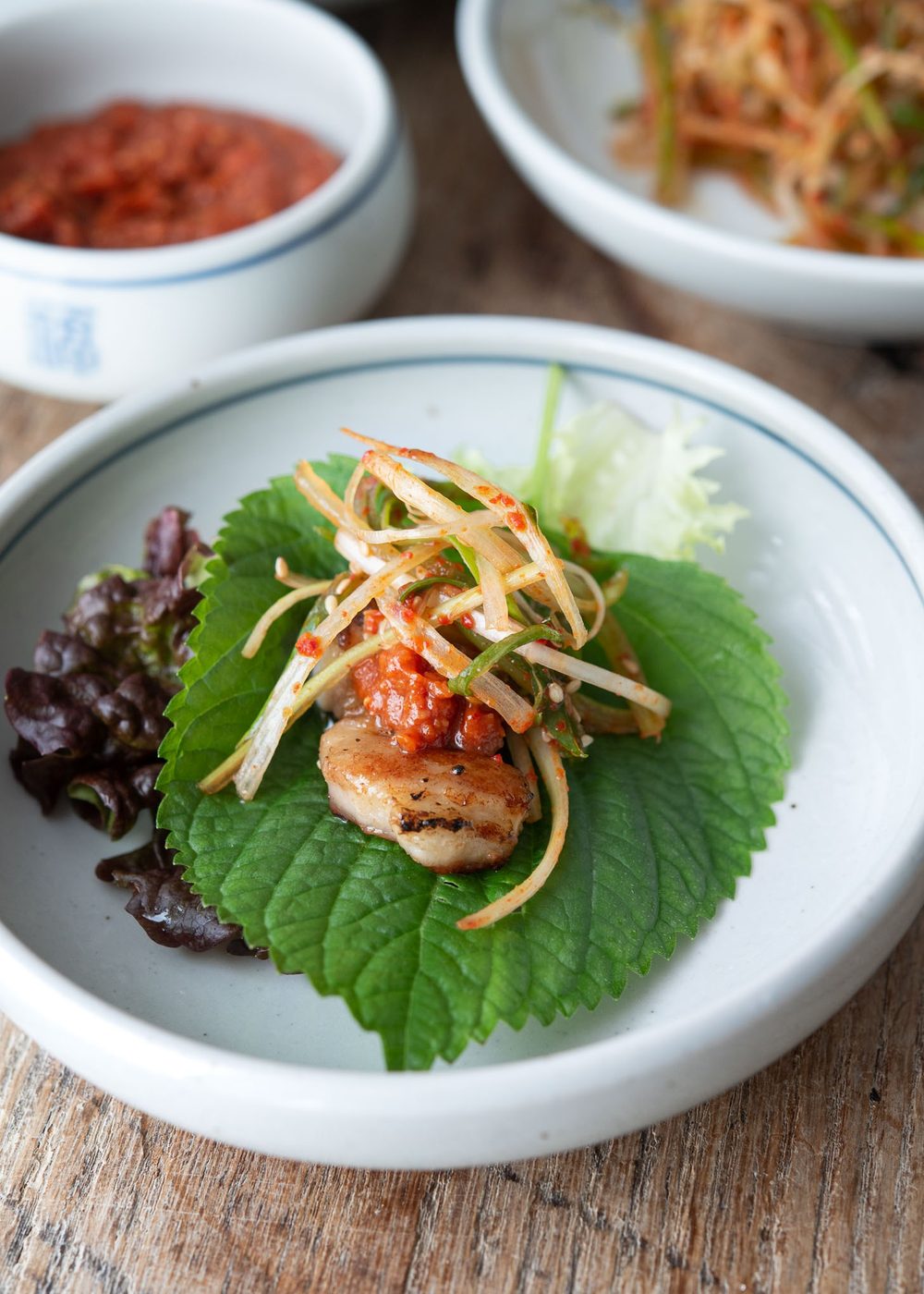 Pa muchim is topped over meat in Korean wrap dish.