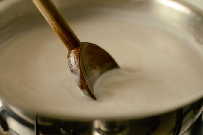 A wooden spoon stirring jelly mixture in a pot.