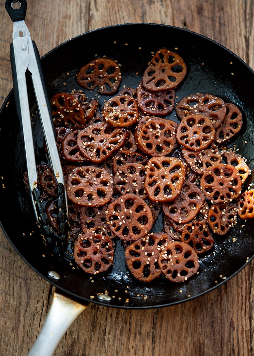Braised Korean lotus root simmering in a glossy soy glaze in a skillet