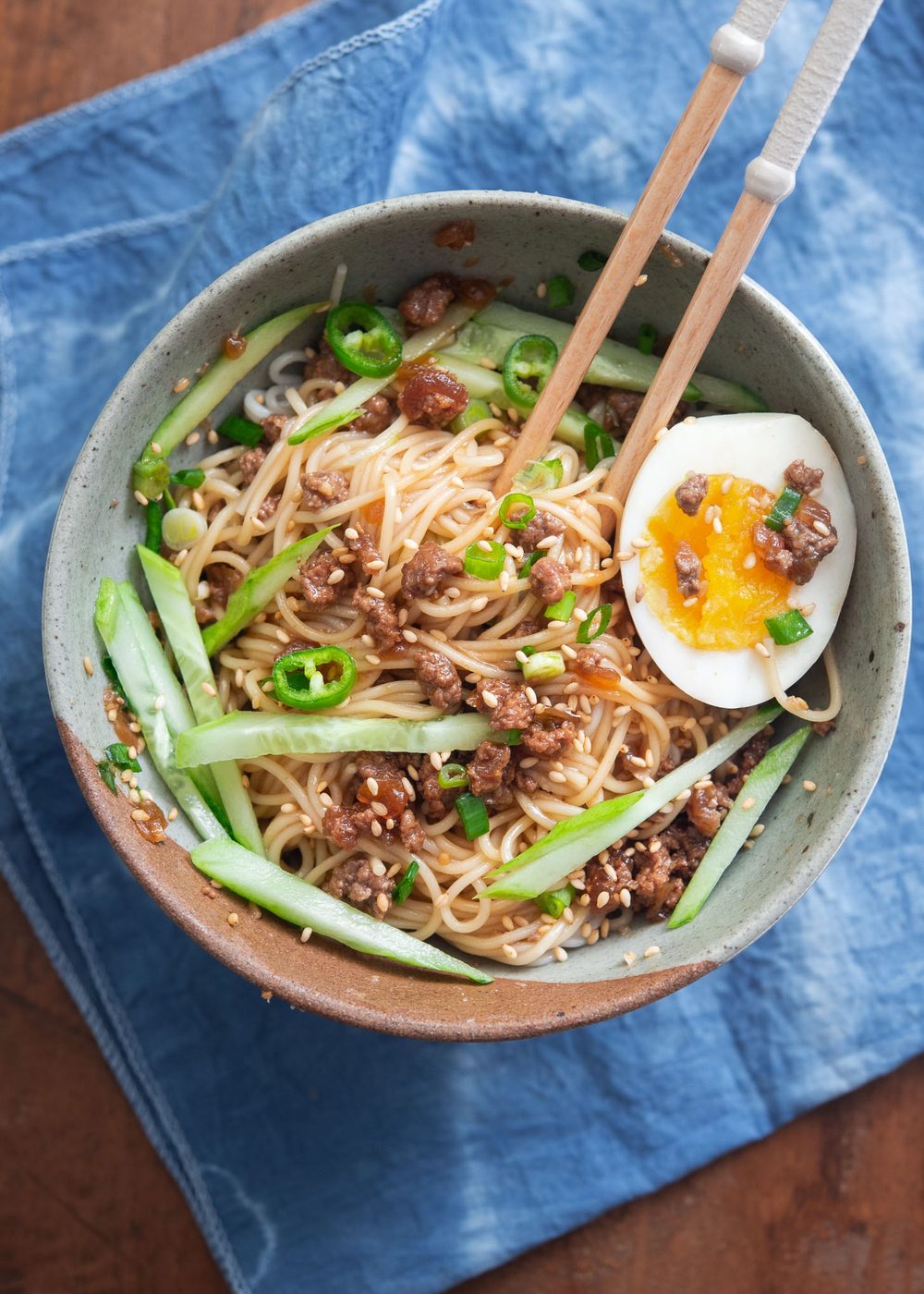 A bowl of ground beef noodles with cucumber and egg.