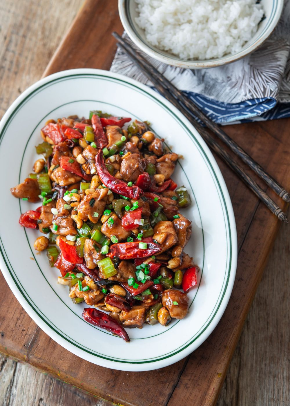Kung pao chicken is served on a platter with a bowl of rice on the side.