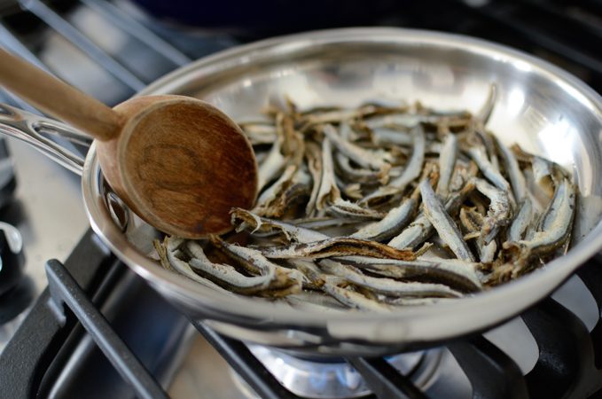 Toasting anchovies in a skillet.