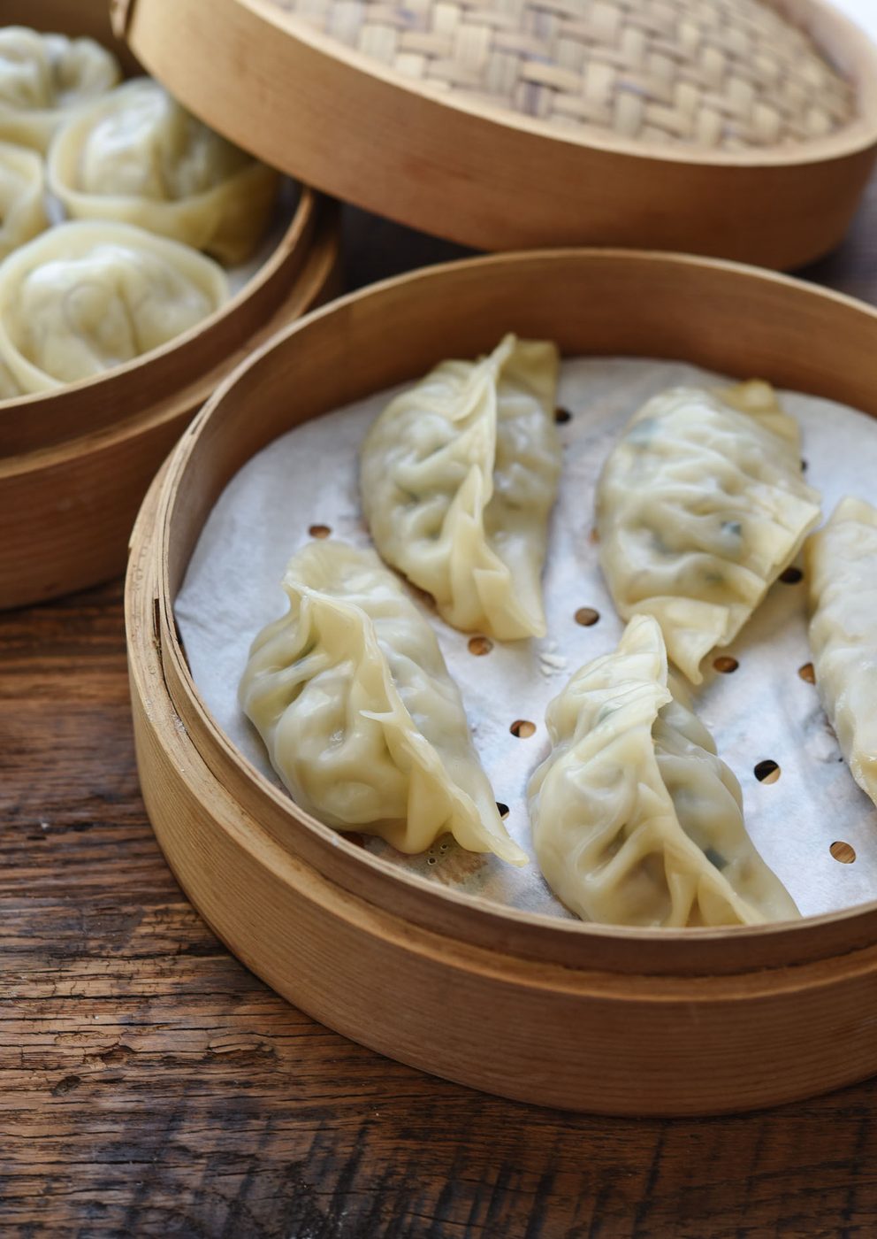 Steamed mandu with pleated tops arranged in a bamboo steamer