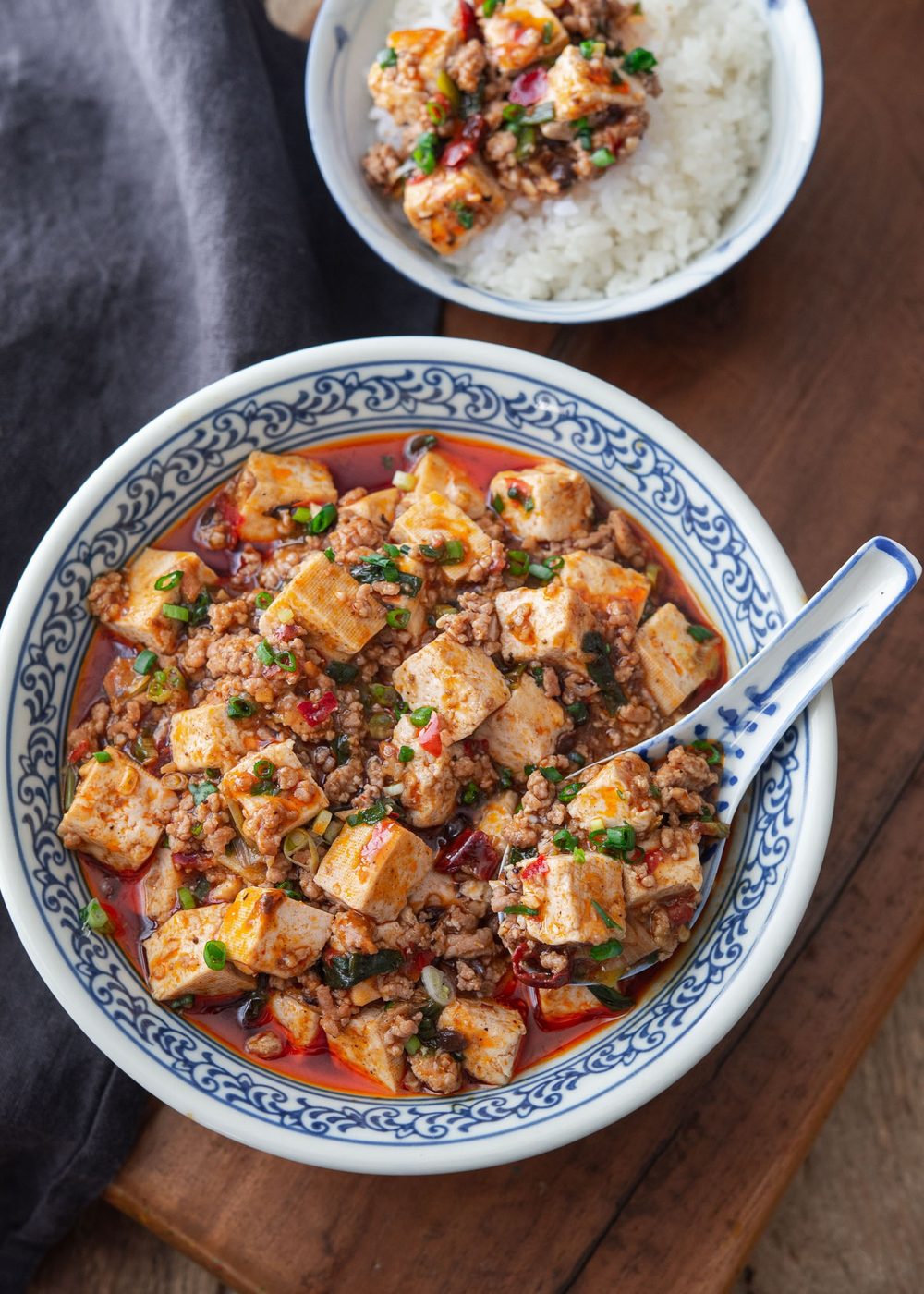 Mapo tofu is dished in a blue bowl with a spoon.