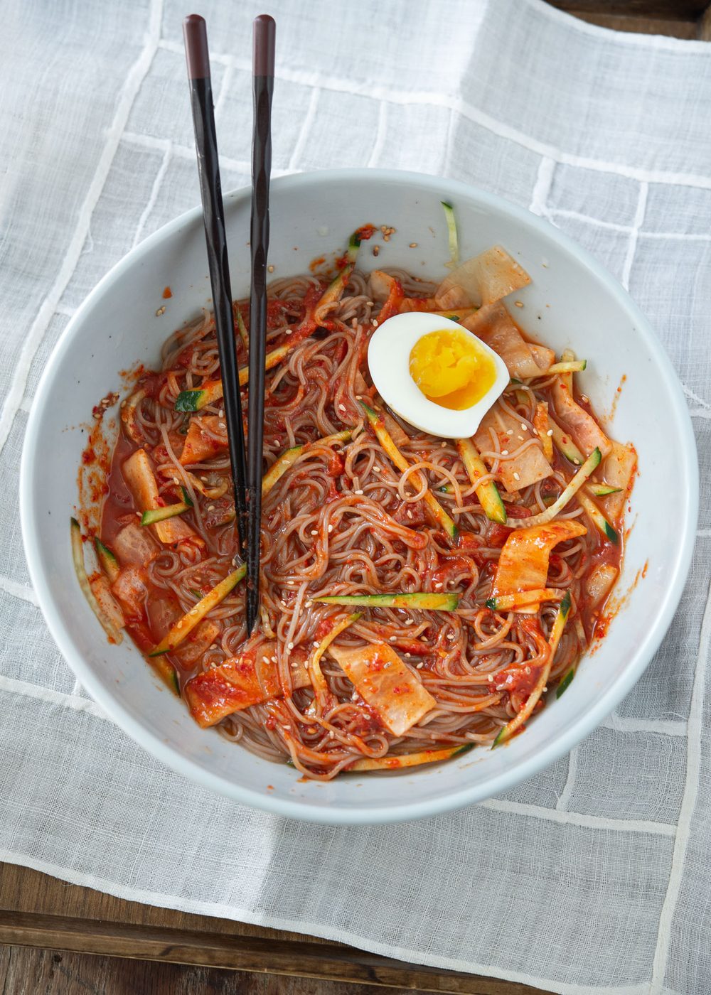 Korean cold buckwheat noodles tossed with spicy red chili sauce until fully coated.