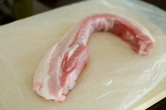 A chunk of pork belly is placed on the board.