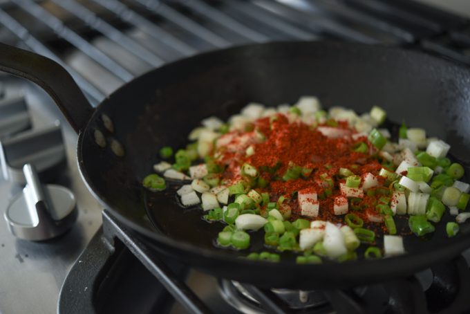Chopped green onion and gochugaru in a skillet.