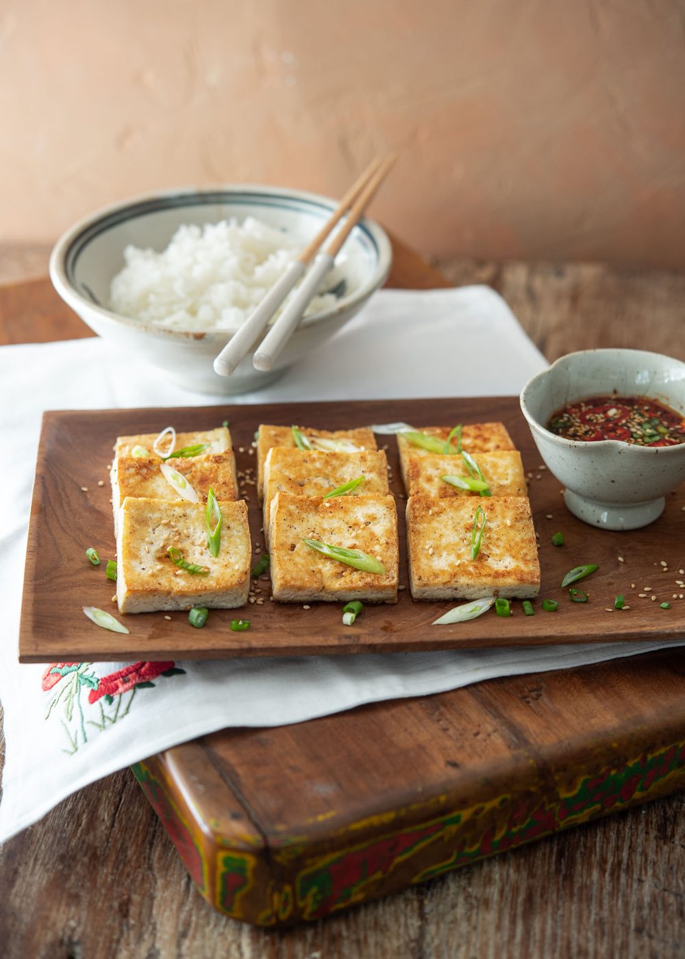 Crispy tofu slices arranged on a platter with soy dipping sauce