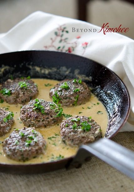 Parsley Peppercorn Beef Patties with cream sauce is prepared in a skillet