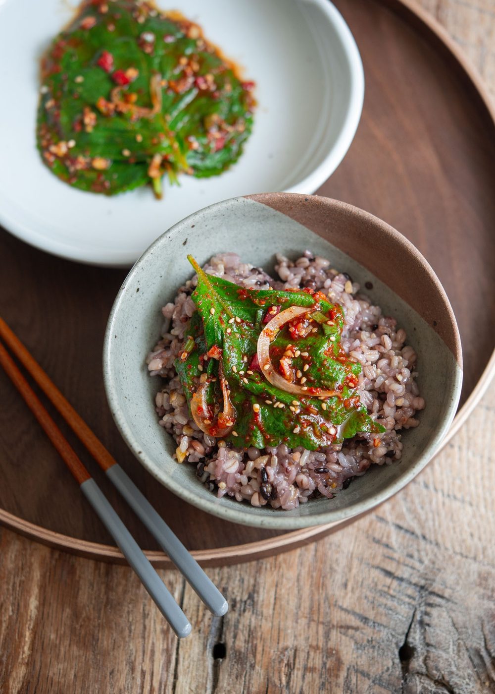 A piece of perilla leaf kimchi placed over a bowl of rice.