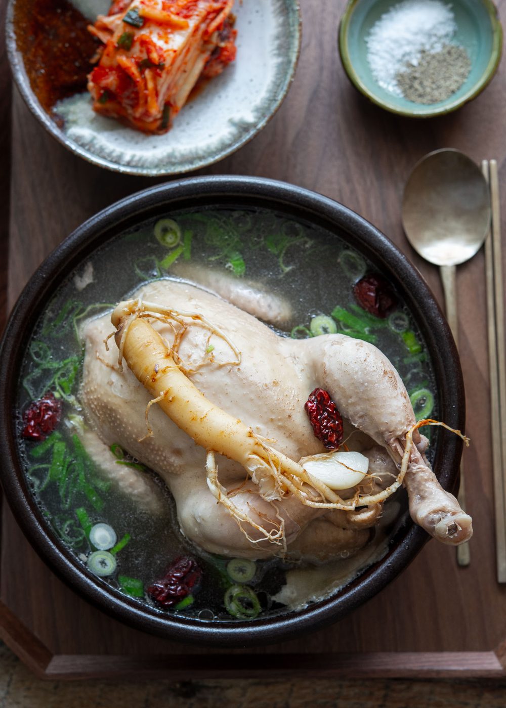 Samgyetang (Korean whole chicken soup) garnished with ginseng in a serving bowl